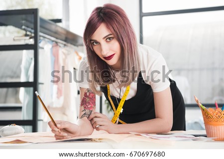 portrait of smiling woman looking at camera while standing at workplace