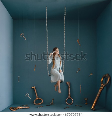 Strange fine art concept of opening your mind. Alice in Wonderland. Girl sitting on a swing with a key in her hand surrounded by many giant keys