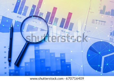 Magnifying glass and documents with analytics data lying on table,selective focus Royalty-Free Stock Photo #670716409