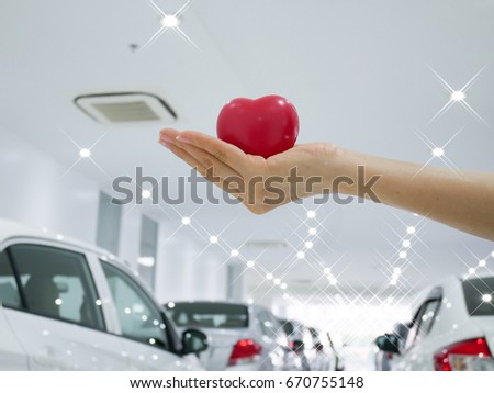 woman hand holding a red heart , blurred car in parking background - Color tone effect .