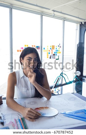 Female architect working on blueprint at her desk in office