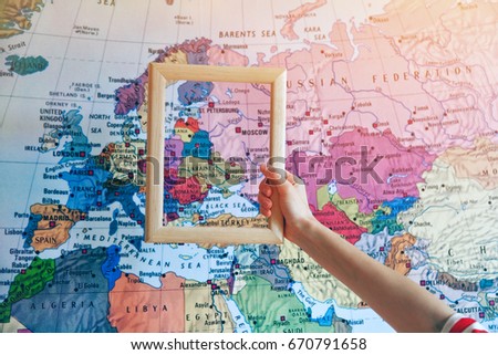 hand holding empty wooden frame on Europe map background
