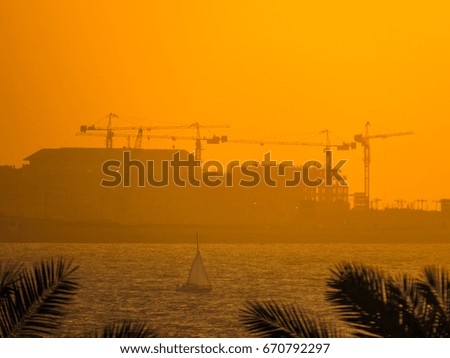 Construction cranes in Dubai at sunset 