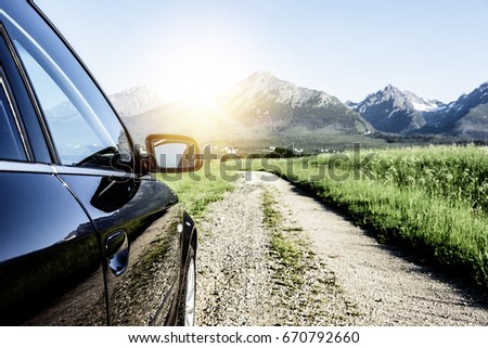 Car is driving on the country road, on the background of rocky mountains.