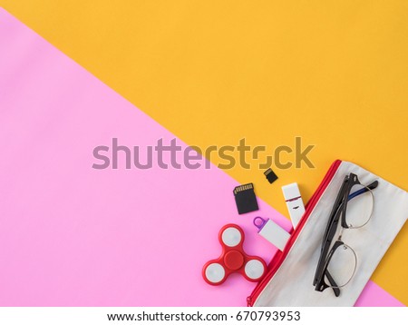 Stationary Background. Flat Lay Photo of Stationary with hand spinner, Glasses, flash drive and stationary on pink and yellow background
