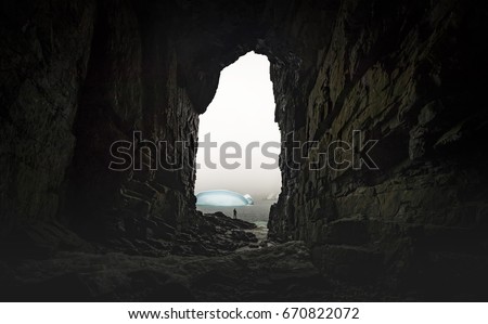 The man stands at the end of the cave in the background of the glaciers. Andreev.