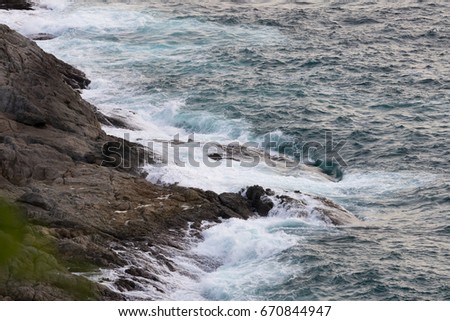 The wave crashing against the rocky shore of the sea