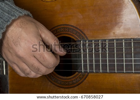 right hand of man who is playing the guitar