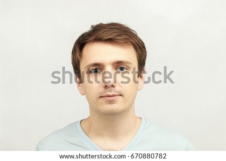 Young, cheerful attractive guy in blue t-shirt and beige shorts holding a sign isolated on white background. A place for your advertising and text.