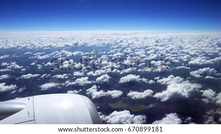 Flying over the clouds. View from plane aircraft passenger window. Clouds and skyline horizon panoramic view. Royalty-Free Stock Photo #670899181