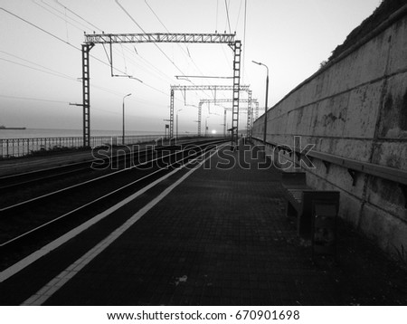 Railroad tracks, old empty apron, electric transmission lines, near the sea. Fashionable grunge background. Black and white photo