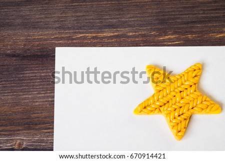 Beautiful yellow star and an empty sheet of paper on wooden background