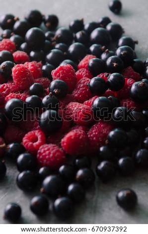 Minimal composition of fresh raspberries and blackcurrants on a concrete background Royalty-Free Stock Photo #670937392