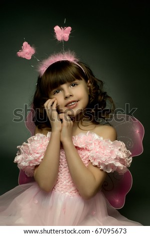 beautiful  little girl with wings, sit and  smile on dark background