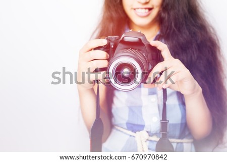 Cute brunette little girl holding an photo camera on white background