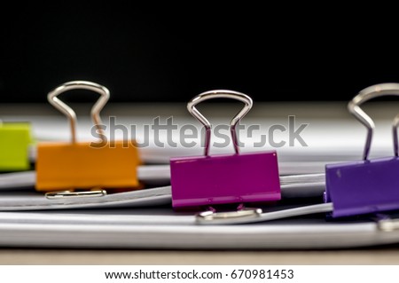 Multiclored paper binders on paperwork close up