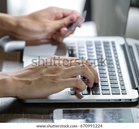 Close up of Human hands using laptop and holding plastic credit card 