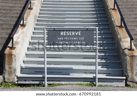 Sign in French language indicating that these staircases are Reserved for Pilgrims Going Up On Their Knees