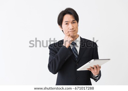 Asian middle age businessman who uses  tablet computer,think,