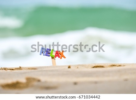 colorful  word RELAX from wooden alphabet  in the sand on the background of beach and sea. 