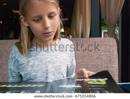 A girl chooses looks at the menu and selects a dish.