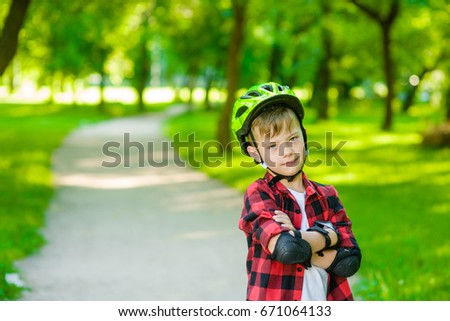 Portrait of a boy with arms crossed in a protective helmet and protective pads for roller skating 