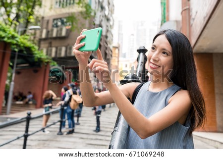 Woman taking photo with cellphone in Pottinger Street
