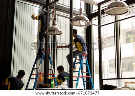 Unidentified worker applying tinted layer on glass window in summer
