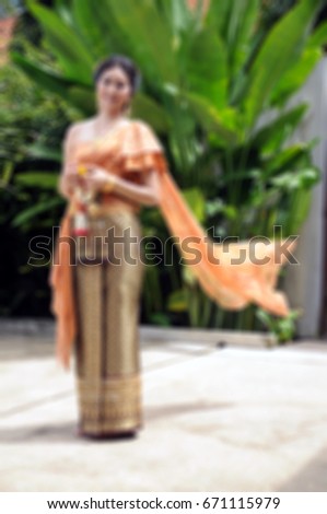 Blur style picture of wedding concept, Thai tradition style of bride with thai garland in hand and disentangle the shawl, and green leaf background of the garden.
