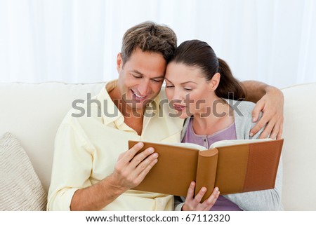 Attentive man and woman looking at a photo album on the sofa in the living room