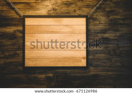 A portrait of a vintage rustic wooden sign hanging on dark wooden wall background, with blank copy space