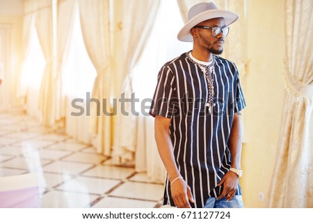 Handsome black man in striped shirt, hat and glasses walking in the restaurant.