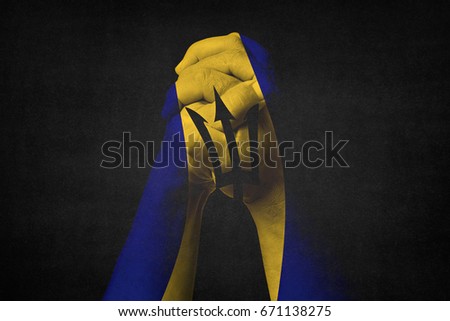 Man clasped hands patterned with the BARBADOS flag,Black background.