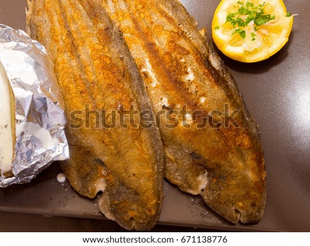 A fish filet in a dish with part of lemon