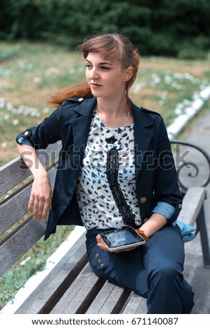 Business lady sitting on a bench with a tablet