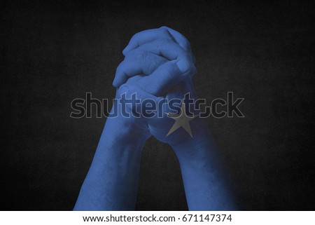 Man clasped hands patterned with the SOMALIA flag.Black background