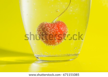 cherry in water with bubbles on a yellow background