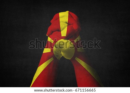 Man clasped hands patterned with the MACEDONIA flag.Black background