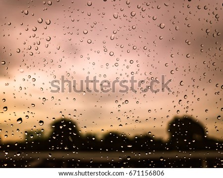Rain drops on the glass, car window, with sunset sky background
