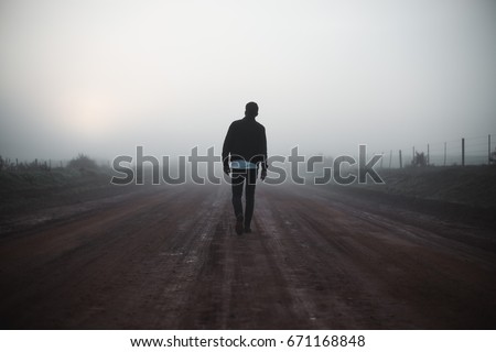 Man walking away on misty road Royalty-Free Stock Photo #671168848