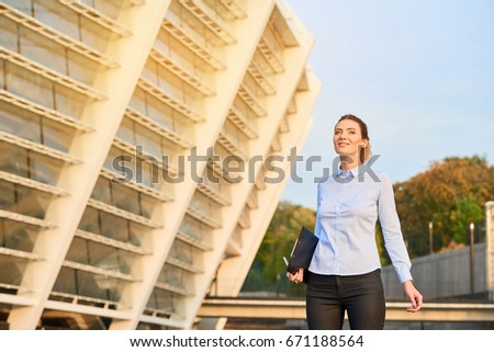 Smiling businesswoman outdoor. Female with a clipboard.