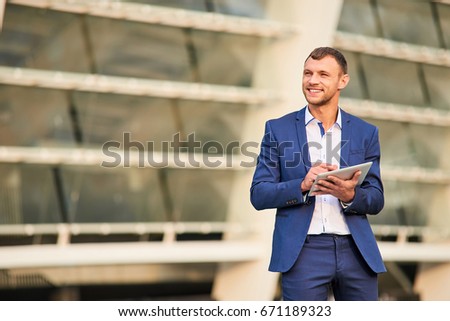 Happy businessman with a tablet. Man in a suit smiling. Discover the world of business.