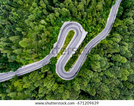 Hairpin turn winding road trough the forest Royalty-Free Stock Photo #671209639