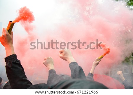 Soccer fans holding up fireworks with thick red smoke of bengal fire Royalty-Free Stock Photo #671221966