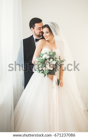 Wedding photo shoot of the newlyweds couple in a beautiful hotel posing near window