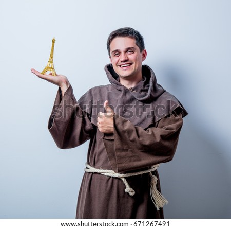 Portrait of Young catholic monk with Eiffel tower gift on white background