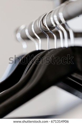 Black empty hangers hanged on rustic poll under shelf in wardrobe. Vertical composition with selective focus on wire, shallow depth of field