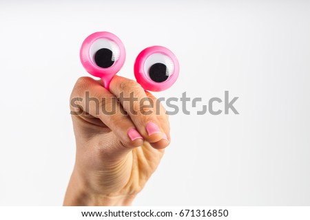 Funny character creature looking very surprised and scared, depicted with female hand and googly eyes. Isolated on white with copy space