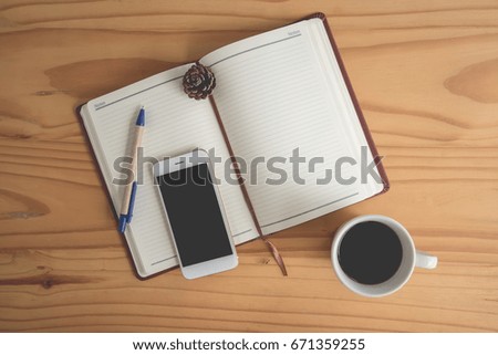 Top view of wood table with notebook,mobile phone ,pen and coffee 