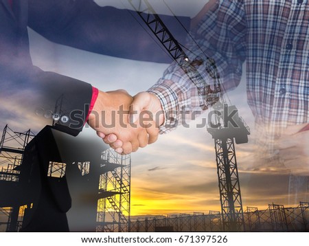 Double exposure photo. Business success concept. Asian businessman and Engineer making handshake together to agree joint business and partnership. Silhouette of scaffolding in the construction site.